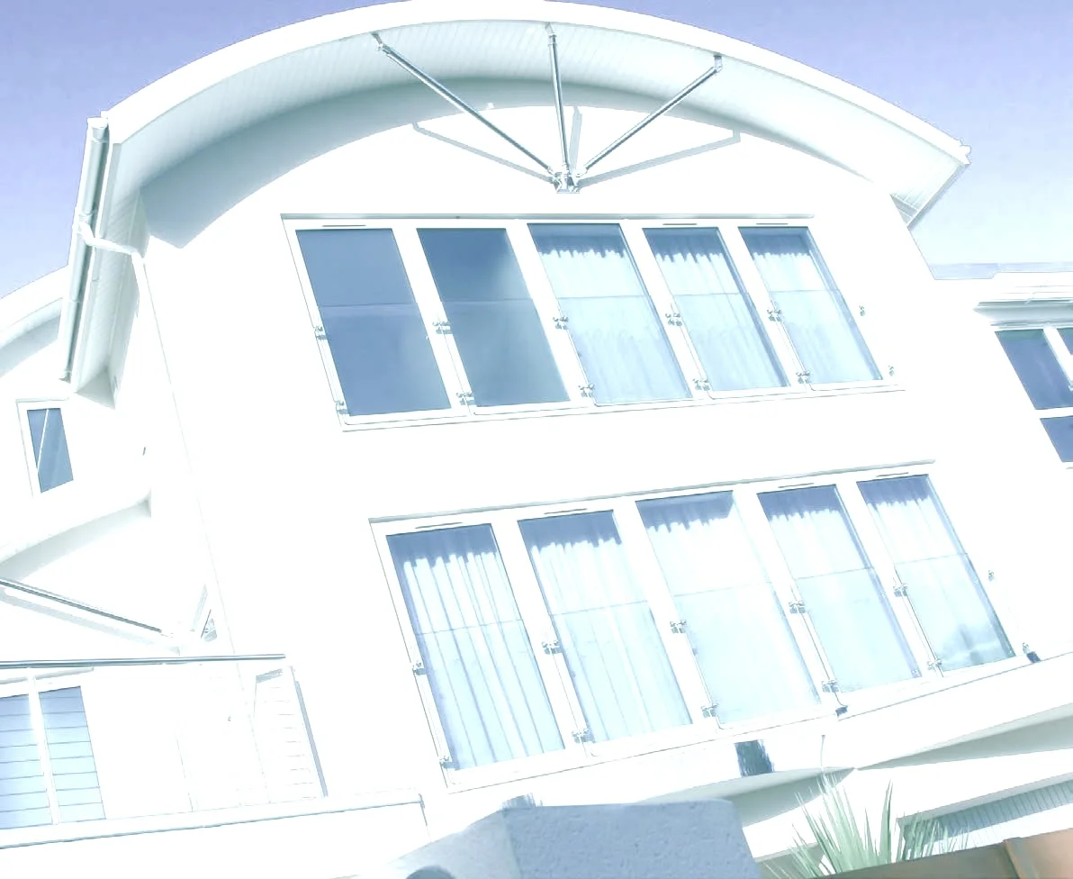 Bâtiment contemporain blanc à toiture arrondie, entièrement vitré par de larges châssis alignés.